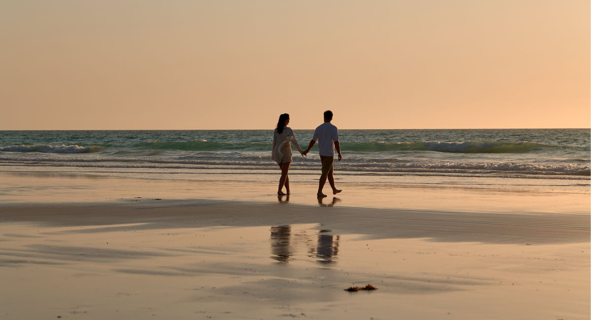 Image of a couple walking across Cable Beach at sunset